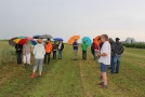 Eine Gruppe von Menschen mit Regenschirmen in der Hand stehen auf einem Feld