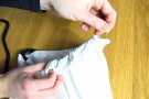 Person fädelt Kordel in einen Beutel ein.