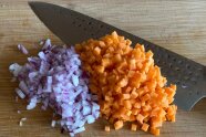 Karotten und Zwiebelwürfel auf einem Holzbrett