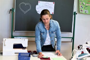 Annika bereitet einen Arbeitsplatz mit Nähutensilien und Nähvorlage vor.