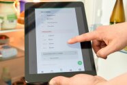 Person verwendet Tablet vor einem Kühlschrank