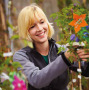 Auszubildende Gärtnerin beim Beschneiden von Blumen