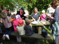 Eltern und Kinder beenden den Bauernhofbesuch mit einer Brotzeit unter freiem Himmel