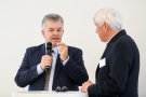 Zwei Herren im Gespräch an einem Podium