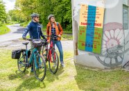 Zwei Radfahrer blicken auf Plakat