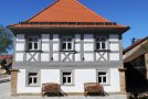 Saniertes zweigeschossiges Fachwerkhaus mit grauem Fachwerk und rot gedecktem Walmdach
