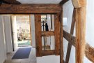 Innenansicht des Hausgangs mit saniertem gut sichtbarem Holztragwerk und weißen Wänden