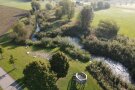 Eine Erholungsoase am Bach mit Ausblicksturm, Sitzmöglichkeiten und Bäumen.