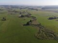 Ein Bach der sich durch die Landschaft schlängelt. Drumherum viele grüne Wiesen.