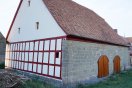 Sanierte landwirtschaftliche Scheune aus Sandstein mit neuer Biberschwanzdeckung, rotem Fachwerk und zwei neuen Holztoren