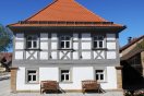 Saniertes zweigeschossiges Fachwerkhaus mit grauem Fachwerk und rot gedecktem Walmdach