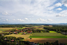 Dorf, umgeben von landwirtschaftlichen Flächen in bewaldeter Region