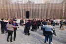Festlichkeit auf dem neuen Dorfplatz. Viele Menschen in Tracht tanzen auf der Freifläche.