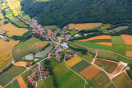Vogelperspektive auf eine Ortschaft. Links unten und rechts oben Wasserrückhaltungen. Rechts unten neue angelegte Wasserrückhaltung mit Staudamm.