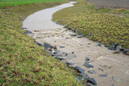 Umgehungsgerinne, das Wasser gefahrlos am Ortsrand vorbeiführt; Wall und Überlaufbereich aus großen Steinen verringern Abflussgeschwindigkeit und Erosion der Sole