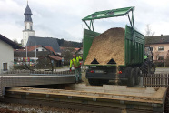 Landwirtschaftliches Fahrzeug kippt für die in der Schule untergebrachte Hackschnitzelheizung zur Nahwärmeversorgung Hackschnitzel in einen Schüttcontainer