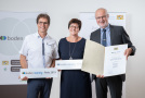 Zwei Männer und eine Frau mit Urkunde