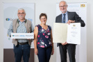 Zwei Männer und eine Frau mit Urkunde