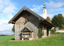 Im Vordergrund ein Schuppen am Hang. Im Hintergrund ein Kirchturm
