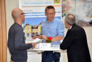 Drei Personen tauschen sich an einem Stehtisch vor einem Exponat zum Projekt aus