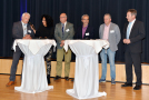 Fünf Referenten sowie Moderatorin stehen an zwei Stehtischen und halten Kurzvorträge