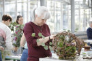 Eine Frau macht aus Weinruten ein dekorative Kugel