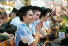 Junge Frauen in Tracht sitzen am Biertisch und applaudieren