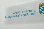 Schild mit blauem Schriftzug und Staatswappen