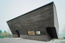Futuristischer, schräger Holzbau mit dunklem Holz