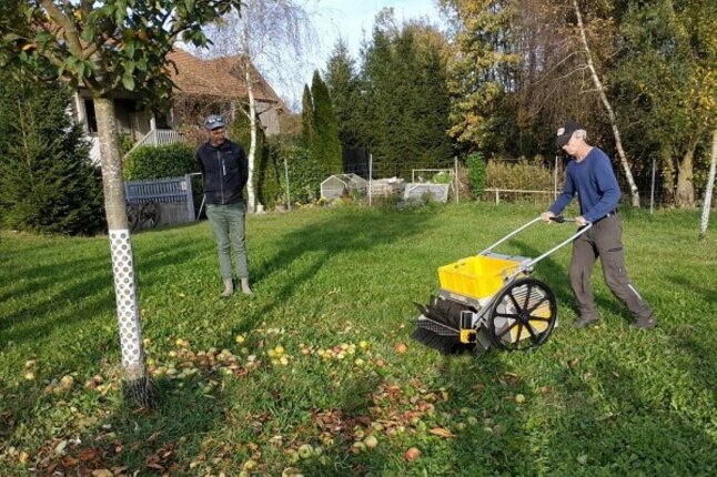 Peron auf einer Streuobstwiese mit einer Erntemaschine zum Schieben.