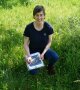 Franziska Schorr kniet in einer Wiese und bestimmt eine Orchidee