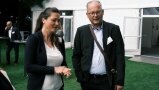 Eine Frau und ein Mann unterhalten sich draußen vor einem Zelt.