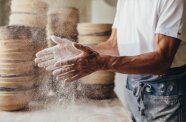 Bio-Bäcker bäckt Brot, schlägt gerade mehlige Hände zusammen
