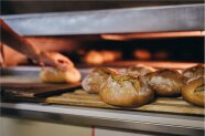 Bio-Bäcker holt Brotlaibe aus dem Backofen