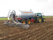 Traktor auf einem Feld mit Anhänger zur bodennahen Gülleausbringung