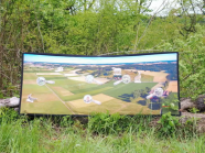 das eine Landschaft zeigende Banner vor einer Hecke