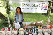 Frau an einem Ausstellungstand mit Streuobstprodukten im Grünen.