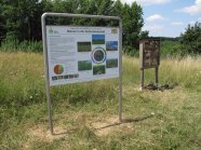 Wiese mit Insektennisthilfe und erklärender Schautafel daneben