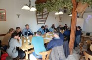 Ca. 20 Personen sitzen an einem großen Tisch und unterhalten sich