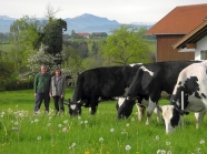 Cilli und Richard Haneberg auf der Weide mit Kühen und Berge im Hintergrund