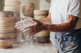 Bio-Bäcker bäckt Brot, schlägt gerade mehlige Hände zusammen