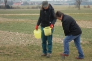 Zwei Frauen bei der Bodenprobenahme auf einem Feld mit Spaten und Eimern.