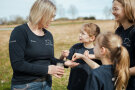 Elisabeth Aue steht mit drei Kindern auf dem Feld, zeigt Getreide in ihrer Hand und redet. 
