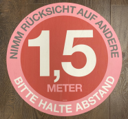 Ein rundes Schild mit der Aufschrift "Bitte Abstand halten"