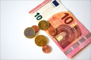 10 EURO Geldschein und sechs Euro Münzen liegen auf einer weißen Fläche