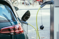 Auto steht in einer Tankstelle mit Zapfhahn in der Tanköffnung 