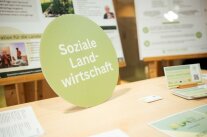 rundes Bild mit der Aufschrift "Soziale Landwirtschaft", das auf einem Tisch steht.