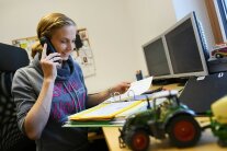 Beraterin schaut eine Mappe im Büro und telefoniert