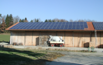 Eine landwirtschaftliche Halle mit einer Photovoltaikanlage auf dem Dach.