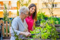 Seniorin und Pflegerin arbeiten im Garten